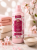 Elegancka aranżacja produktowa w stylu spa. Płyn do płukania Tesori d'Oriente Ikigai w otoczeniu miękkich ręczników, kwiatów wiśni i wody ryżowej. Jasne tło, subtelne światło i harmonijna atmosfera podkreślają wyjątkowy charakter zapachu.